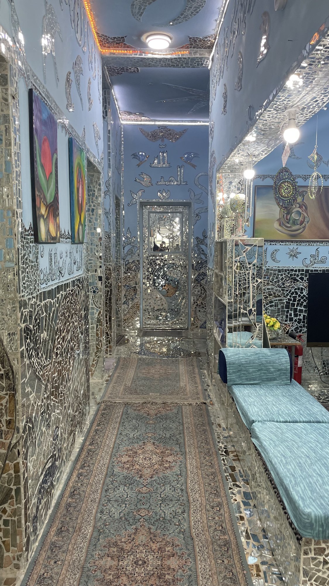 A mirror-clad corridor hung with paintings