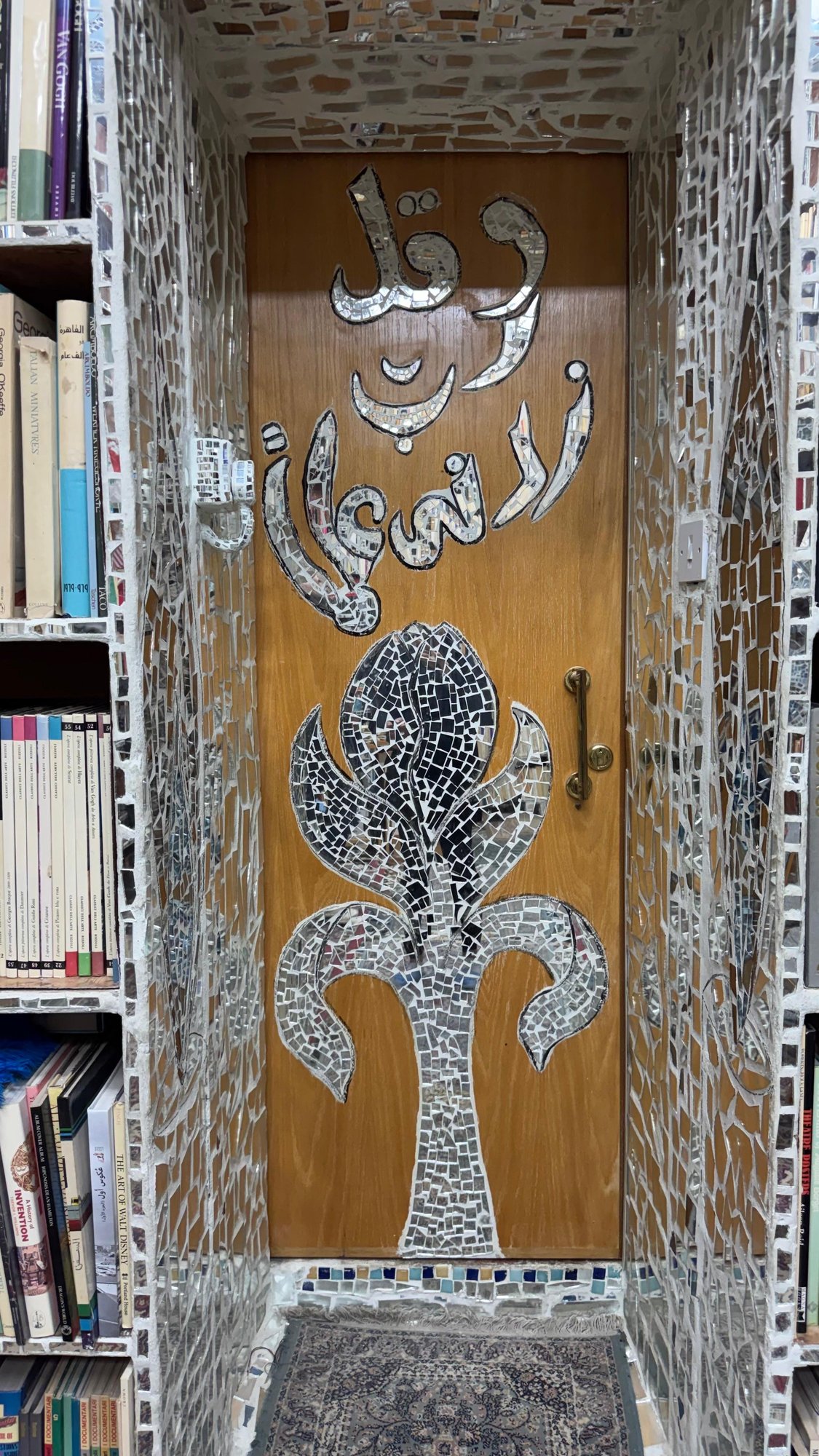 A mirror tree-of-life set into a wooden door among the bookshelves
