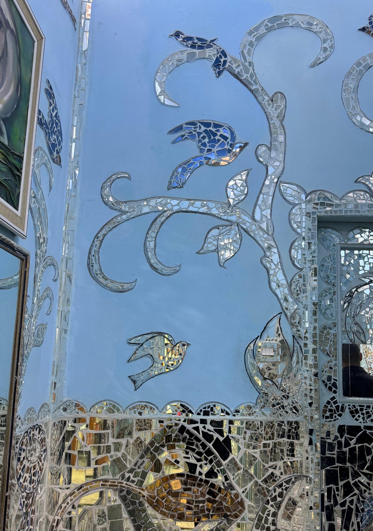 Mirror birds among foliate vines on a blue wall