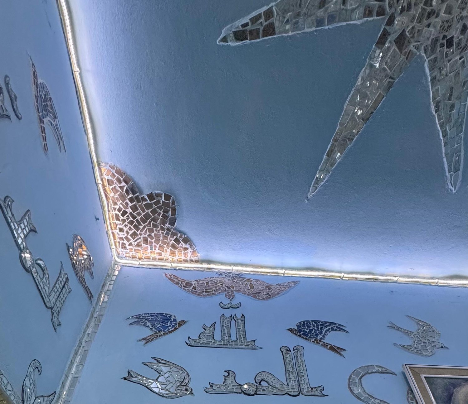Mirror-mosaic doves and calligraphy across a blue ceiling and its corner